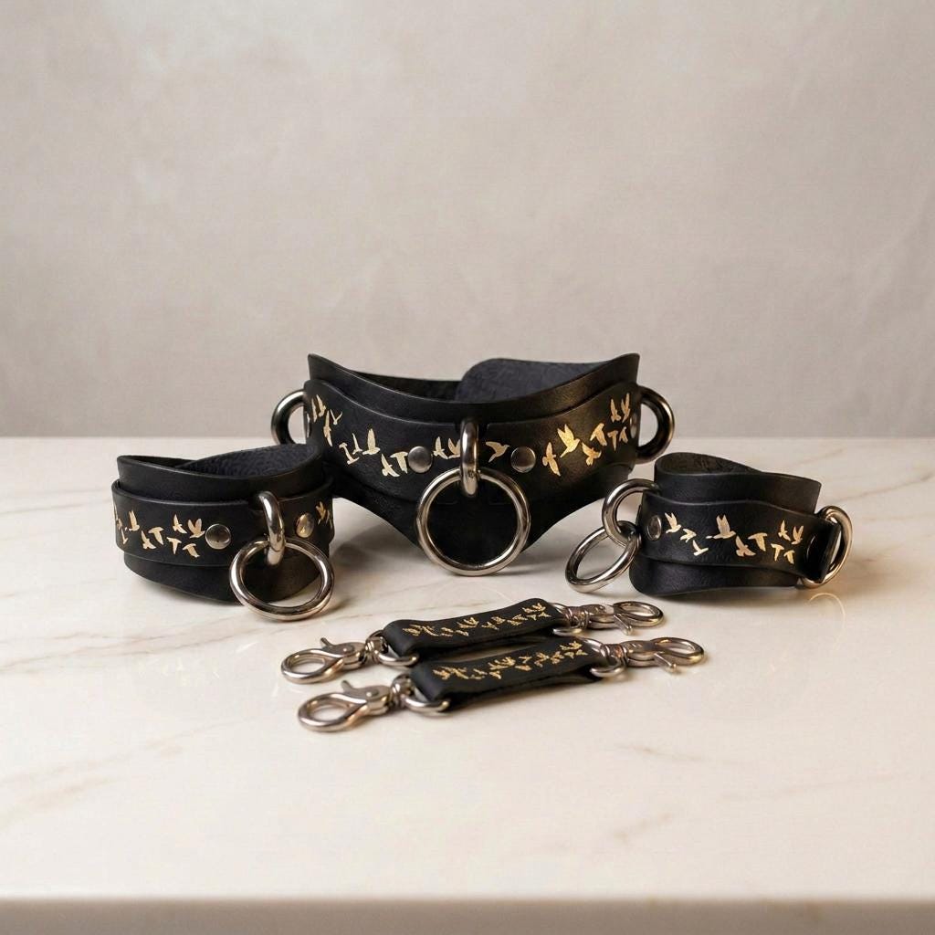a collection of black leather straps with gold leaf designs, arranged on a white marble surface.
