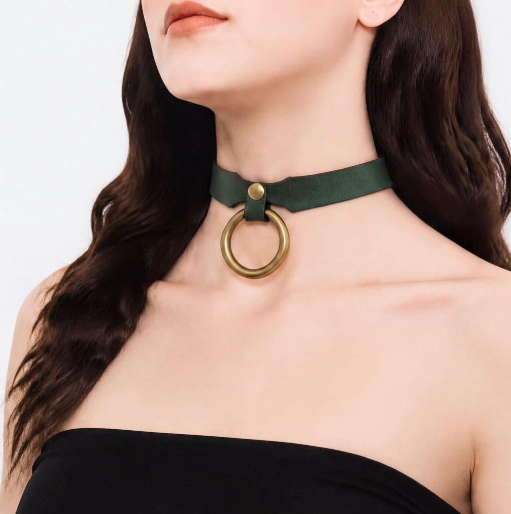 A woman wearing a green choker necklace with a gold ring on it.