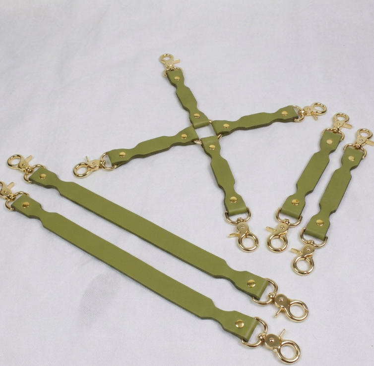 A group of green leather straps with gold metal clasps and buckles, arranged in a cross-like pattern on a white background.