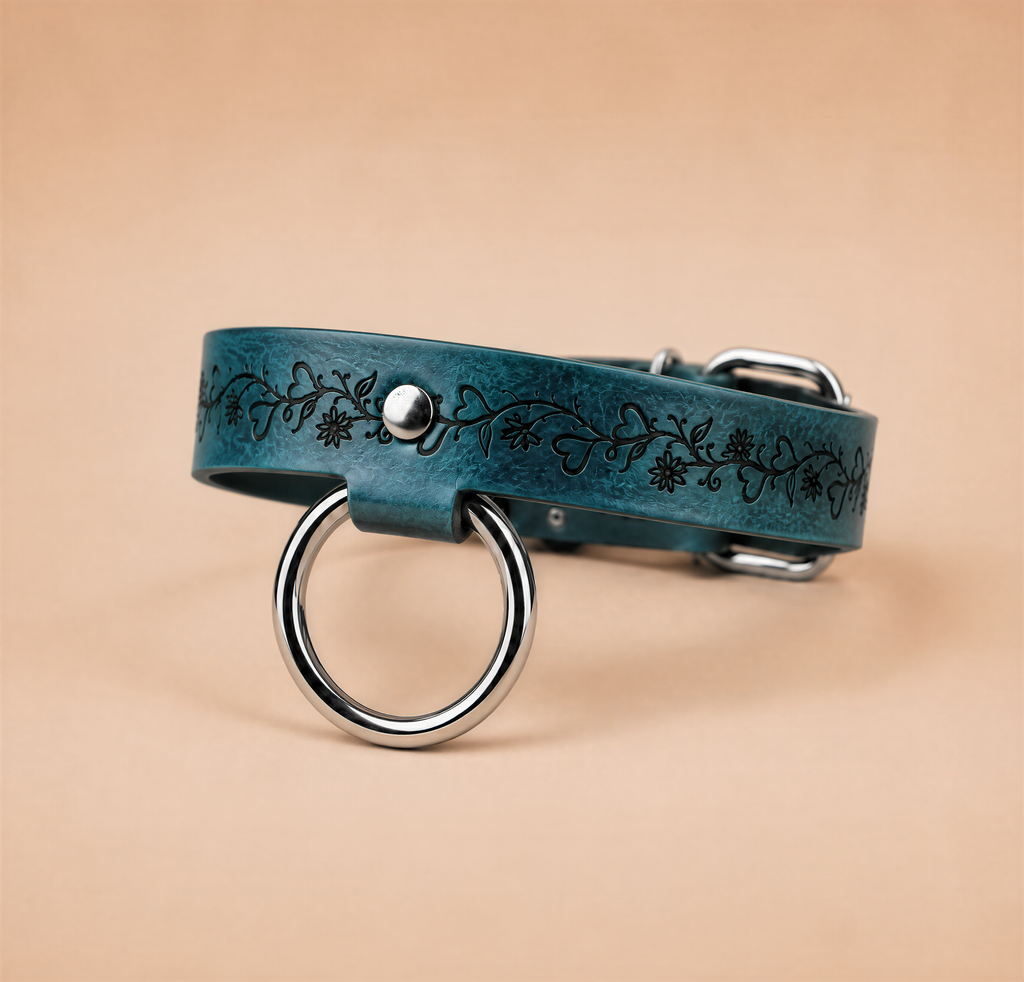 A blue leather collar with a metal ring and a floral design on it.