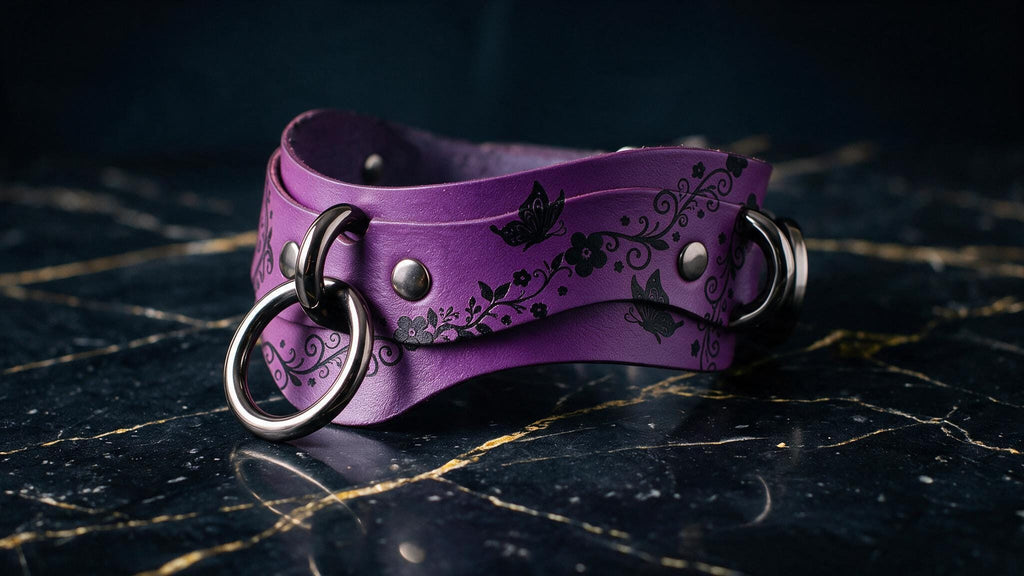 A purple leather choker necklace with a floral design and metal rings is displayed on a dark marble surface.