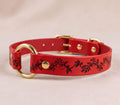 A red leather dog collar with a floral design and gold hardware.