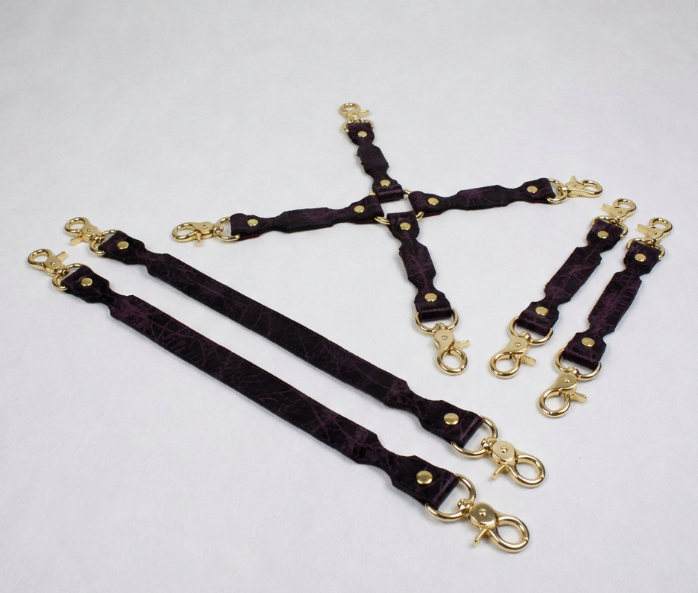 a collection of dark purple leather straps with gold metal clasps and buckles, arranged on a white background.