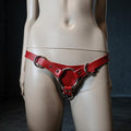 A mannequin wearing a red leather harness with metal rings.