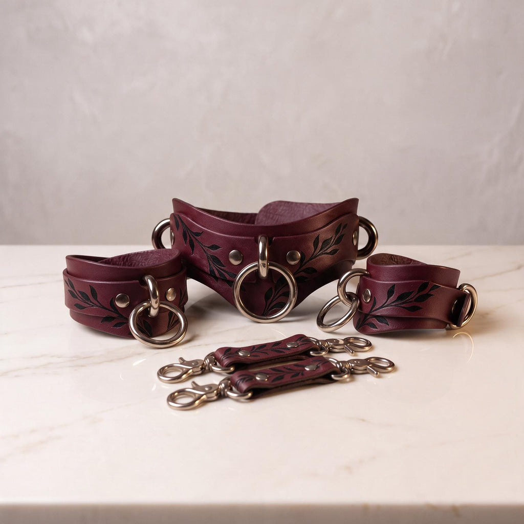 A set of burgundy leather straps with leaf designs, arranged on a white marble surface.