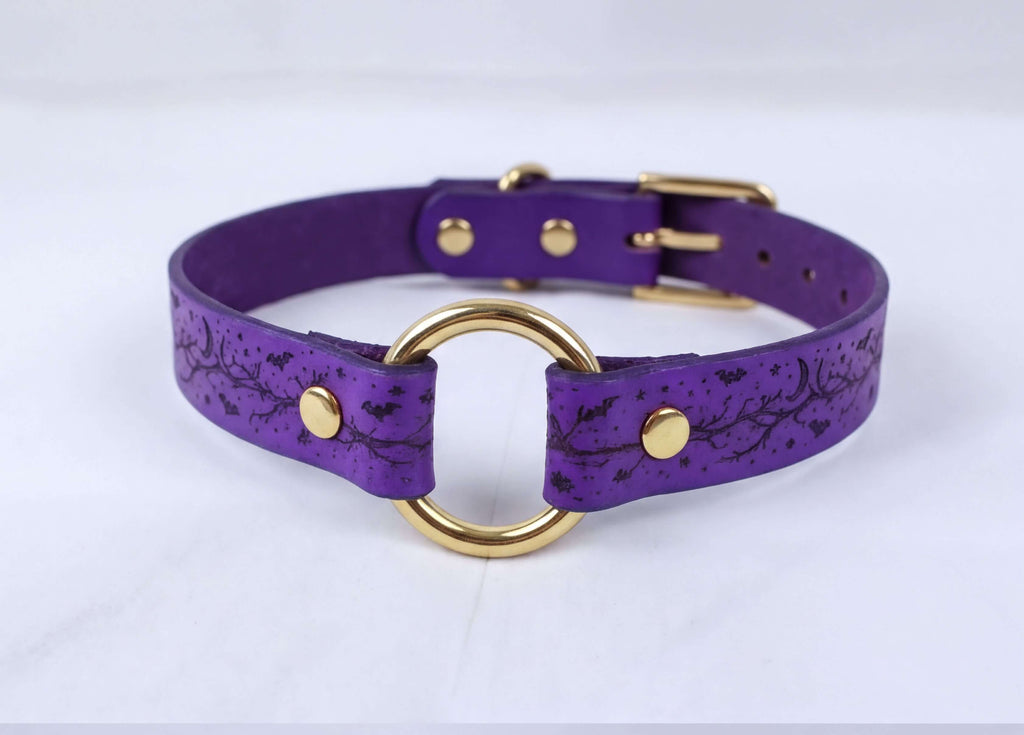 A purple leather collar with a gold-colored metal ring and buckle.