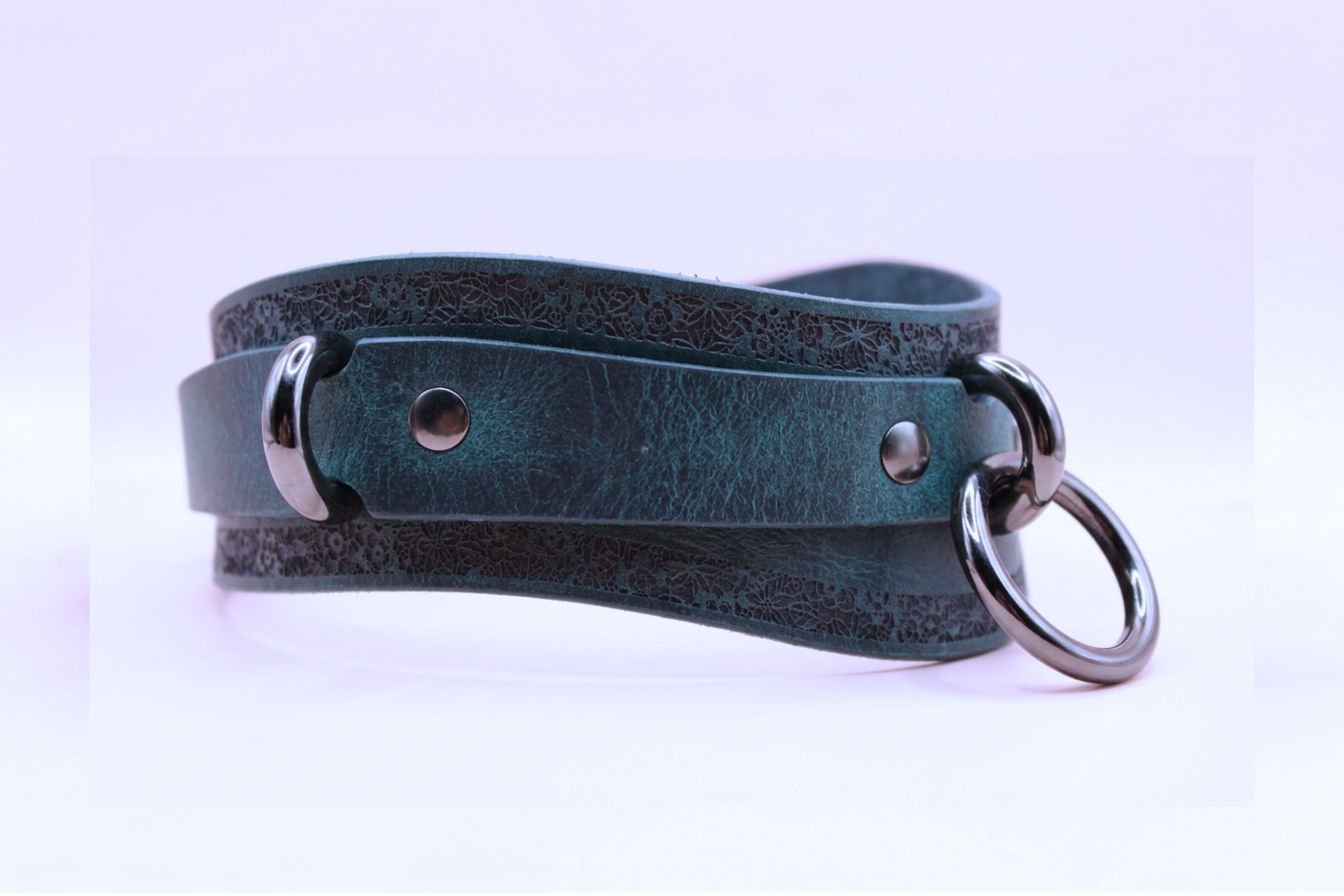 A dark green leather choker necklace with metal rings and a metal clasp.