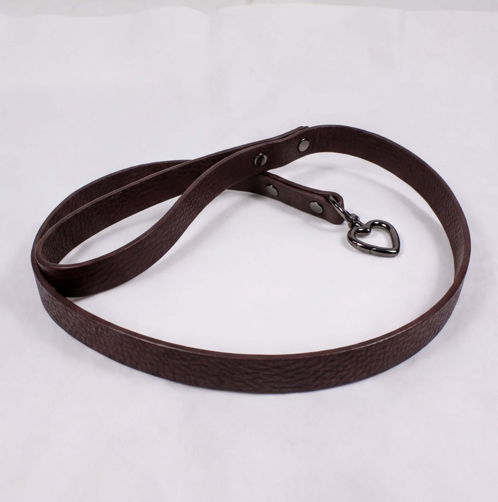 A brown leather dog leash with a heart-shaped charm attached.