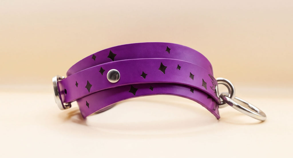 A purple leather strap with black diamond-shaped patterns and metal rings attached to it.