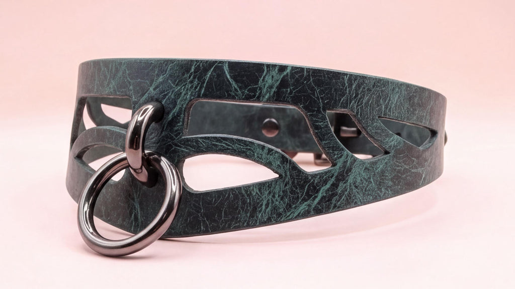 A close-up view of a dark green leather choker necklace with a metal ring and cutout design.