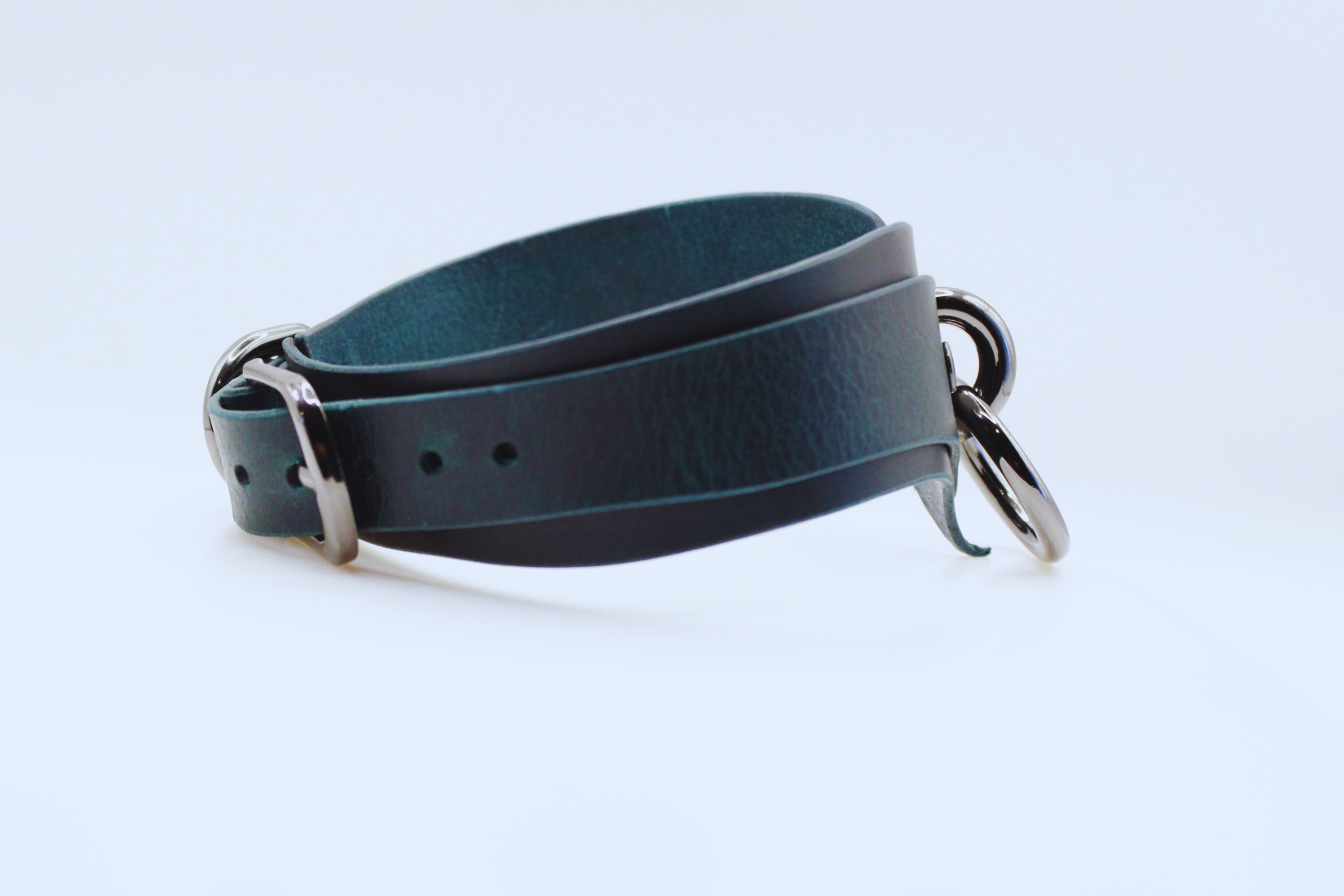 A dark green leather strap with metal buckles and a metal clasp.