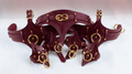A burgundy leather corset with gold-colored metal studs and buckles, displayed on a white background.