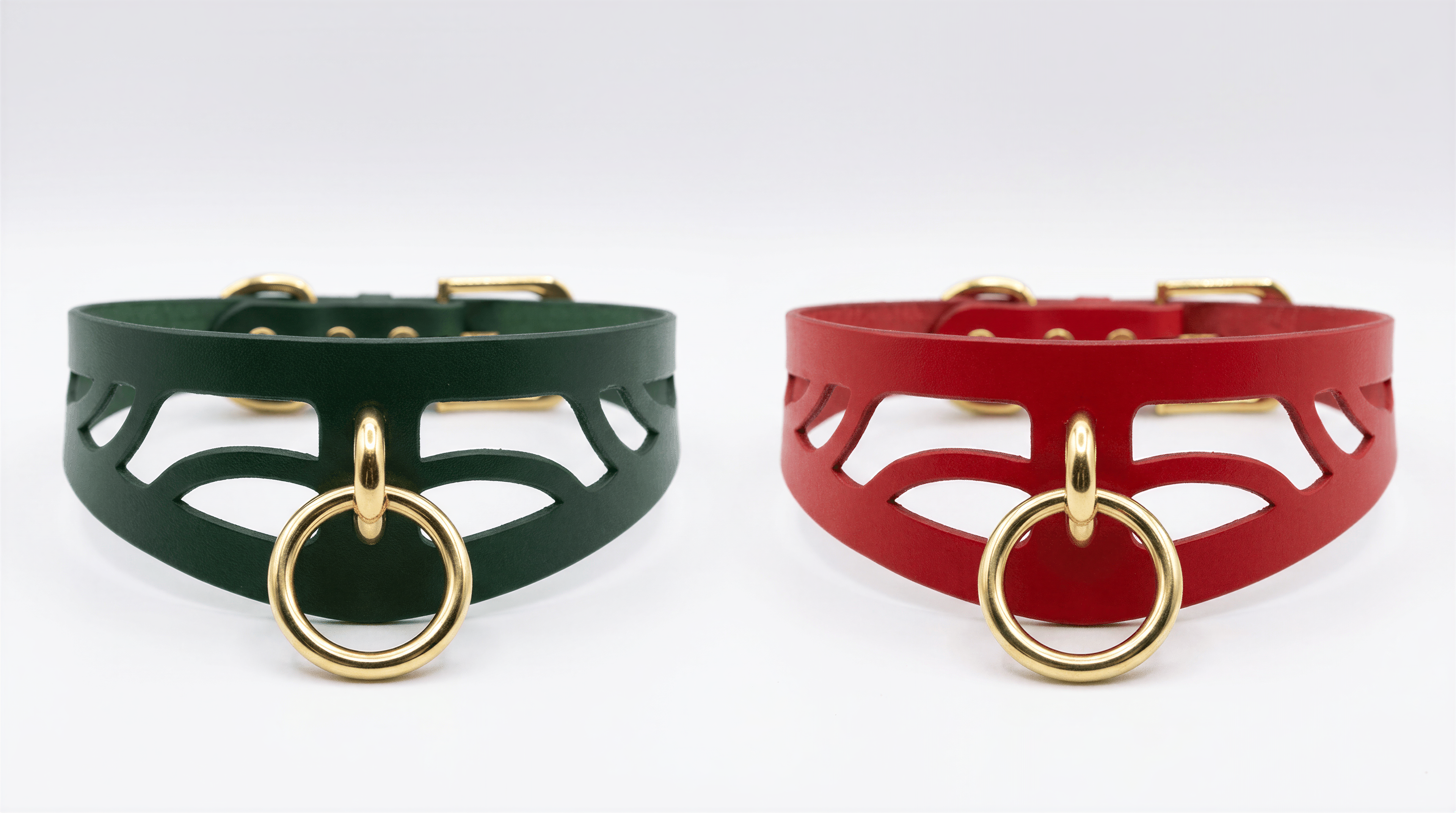 two leather choker necklaces with gold-colored metal rings, one in green and the other in red.