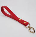 A red leather strap with a heart-shaped metal clasp attached to it.