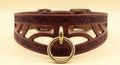 A close-up image of a brown leather collar with a metal ring and a decorative pattern on the surface.