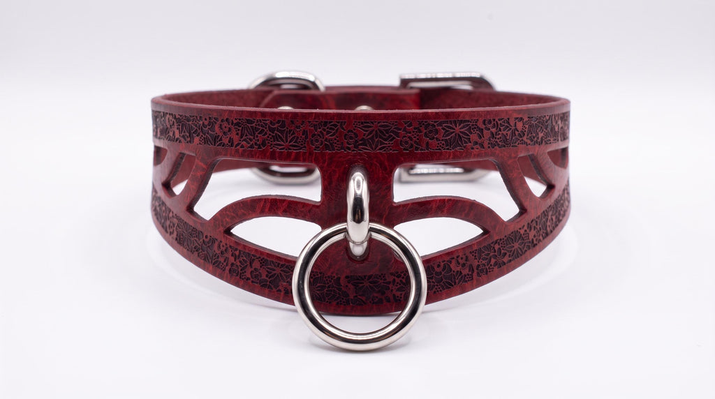 A burgundy leather choker collar with a metal ring and a metal buckle.