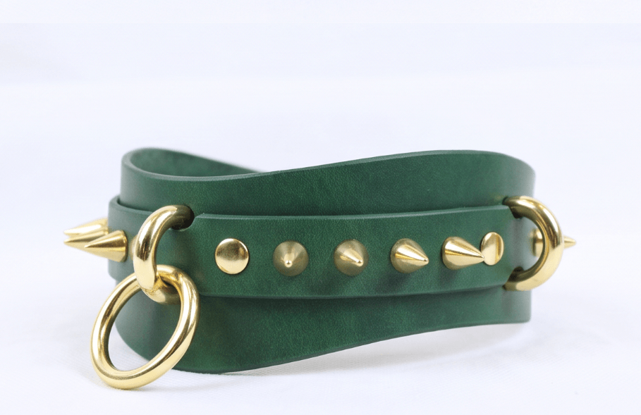A green leather choker necklace with gold studs and a ring.
