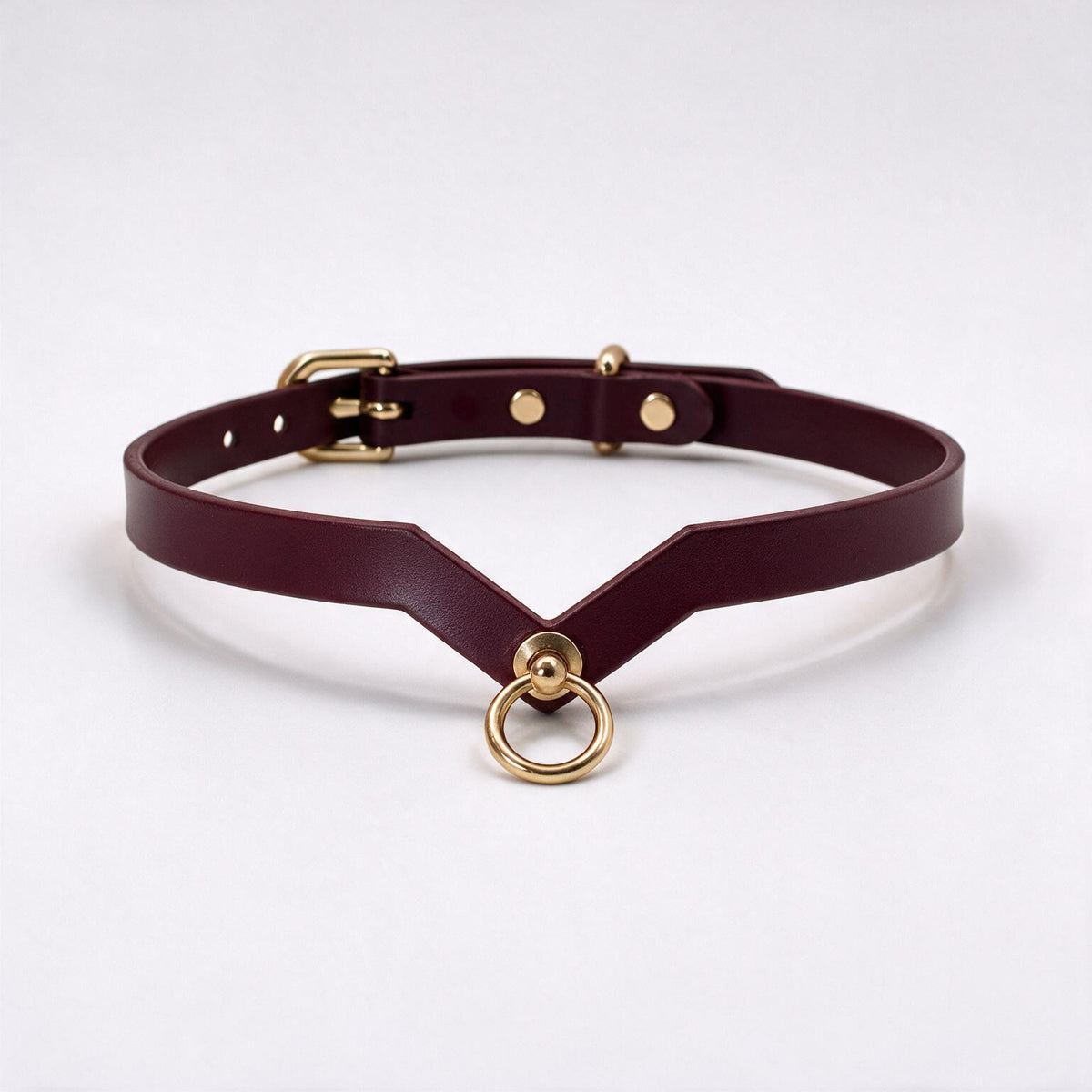 A burgundy leather choker necklace with a gold-colored metal ring and buckle.