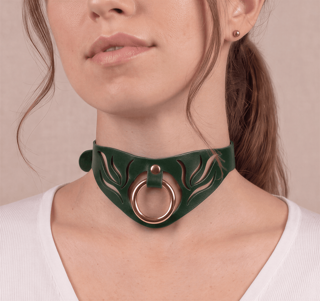 A close-up of a woman's neck and chin wearing a green choker necklace with a gold ring.
