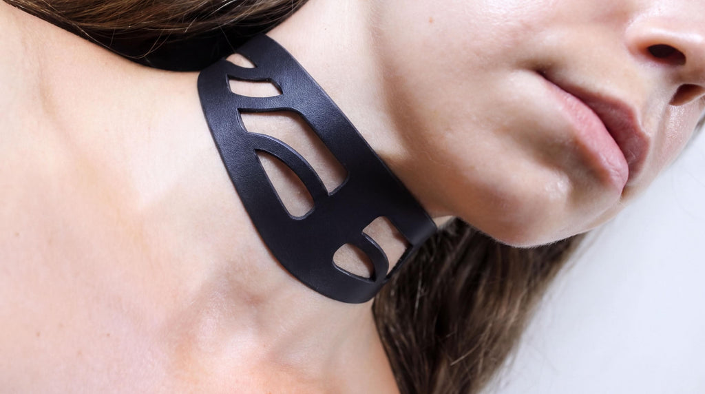 A close-up view of a person's neck and chin area, with a black choker necklace prominently featured.