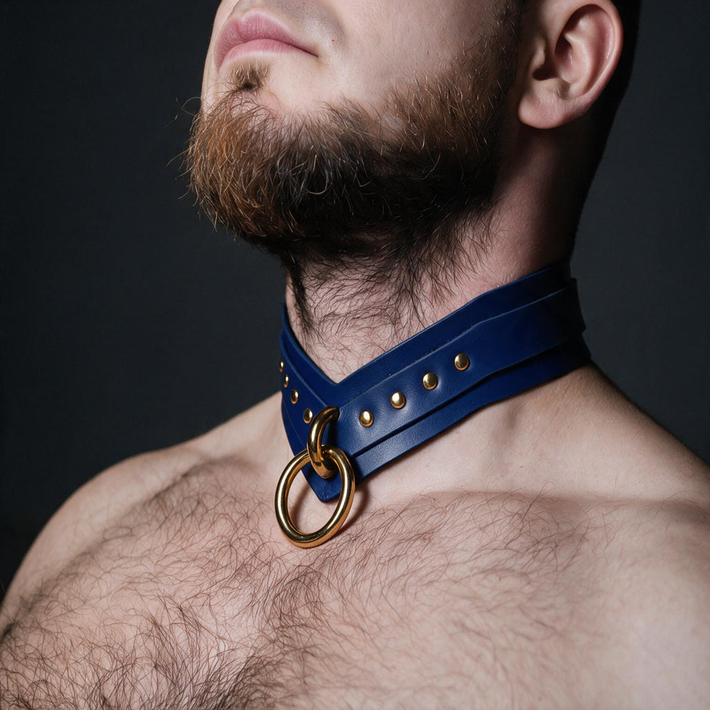 A close-up of a man's neck and chest area, with a blue leather choker necklace featuring a gold ring and studs.