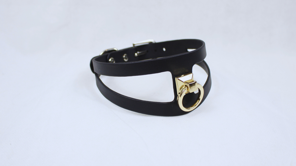 A black leather choker necklace with a gold-colored metal clasp.