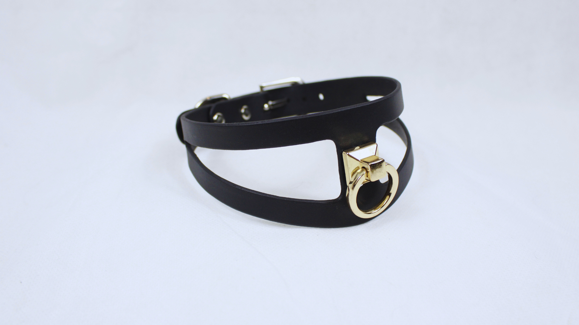 A black leather choker necklace with a gold-colored metal clasp.