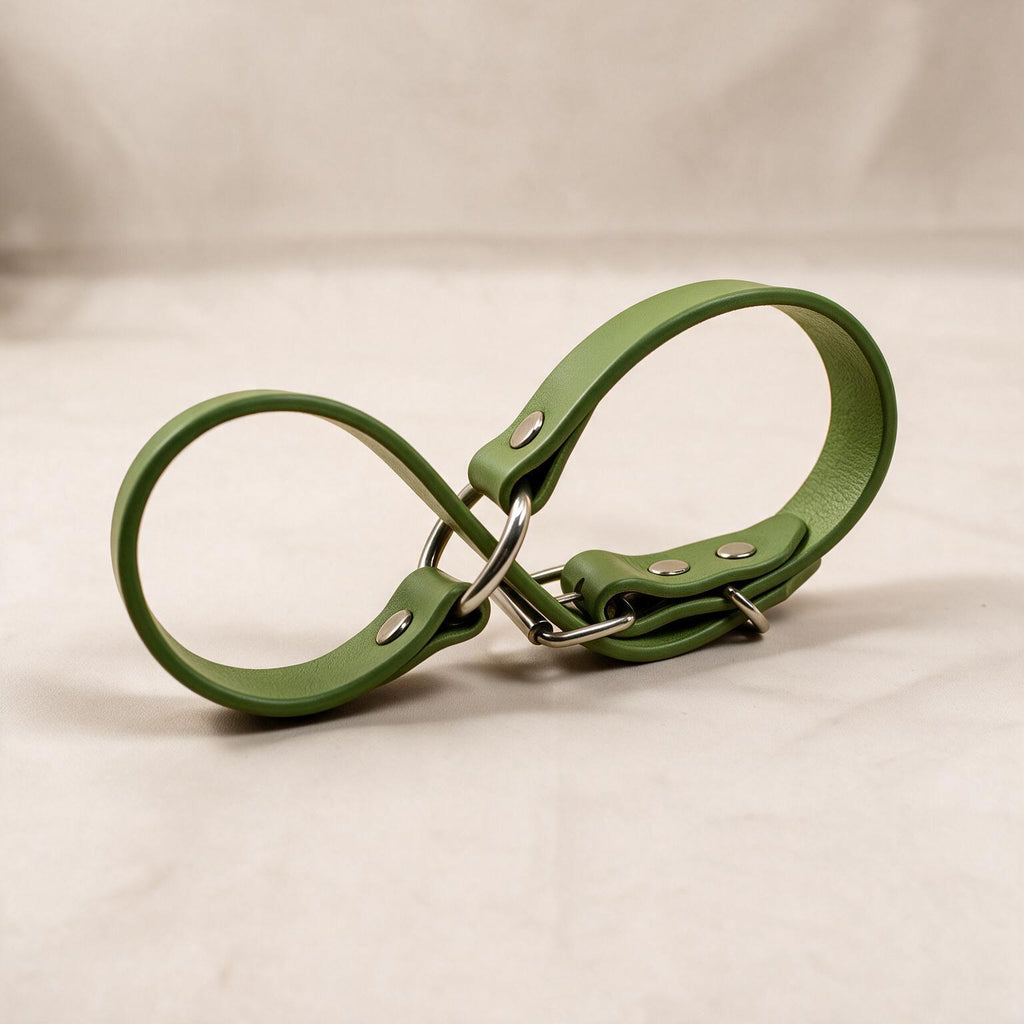 A green leather strap with metal buckles and clips is shown against a light background.