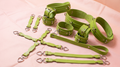 a collection of green leather straps and buckles arranged on a pink surface.
