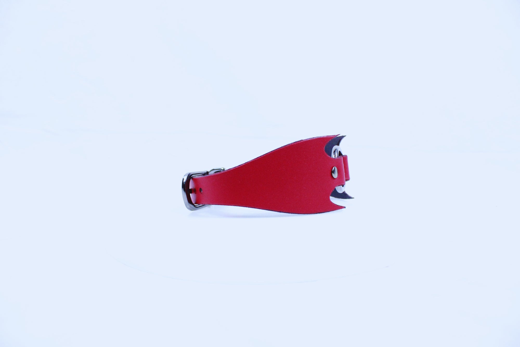 A red, curved object resembling a stylized animal or shape is shown against a plain white background.