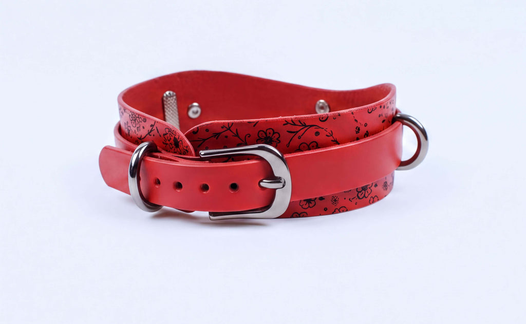 A red leather belt with a floral pattern and metal buckle.
