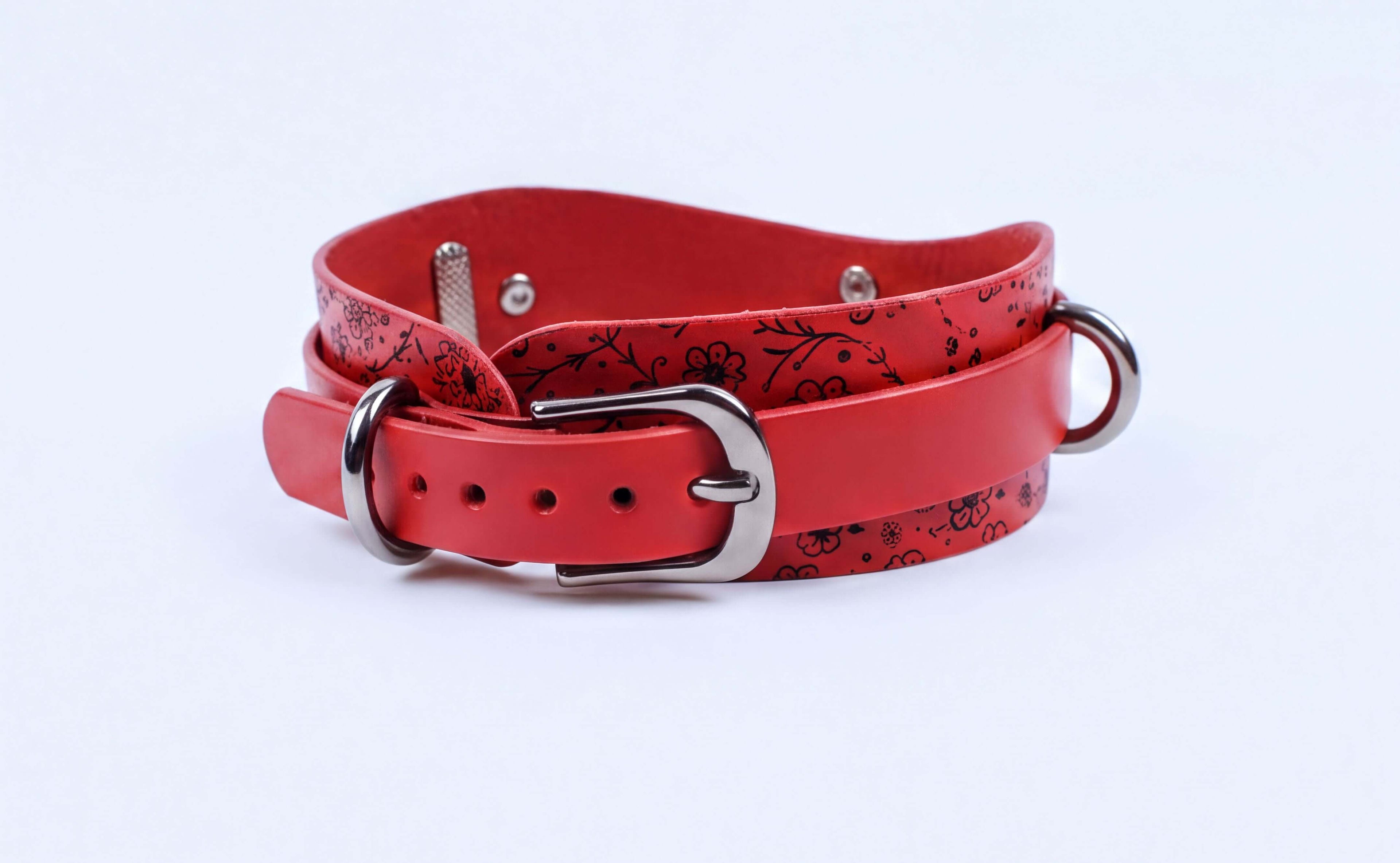 A red leather belt with a floral pattern and metal buckle.