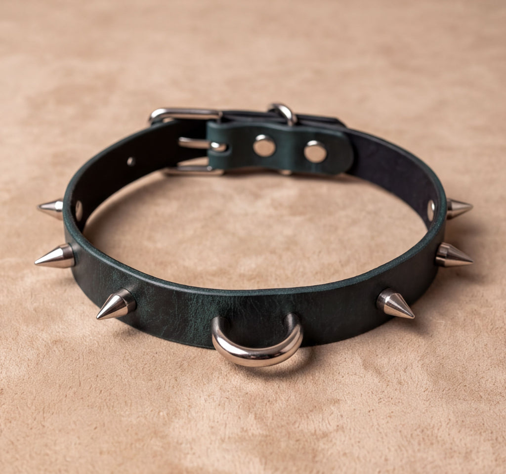 A green leather collar with spikes protruding from it, resting on a beige surface.