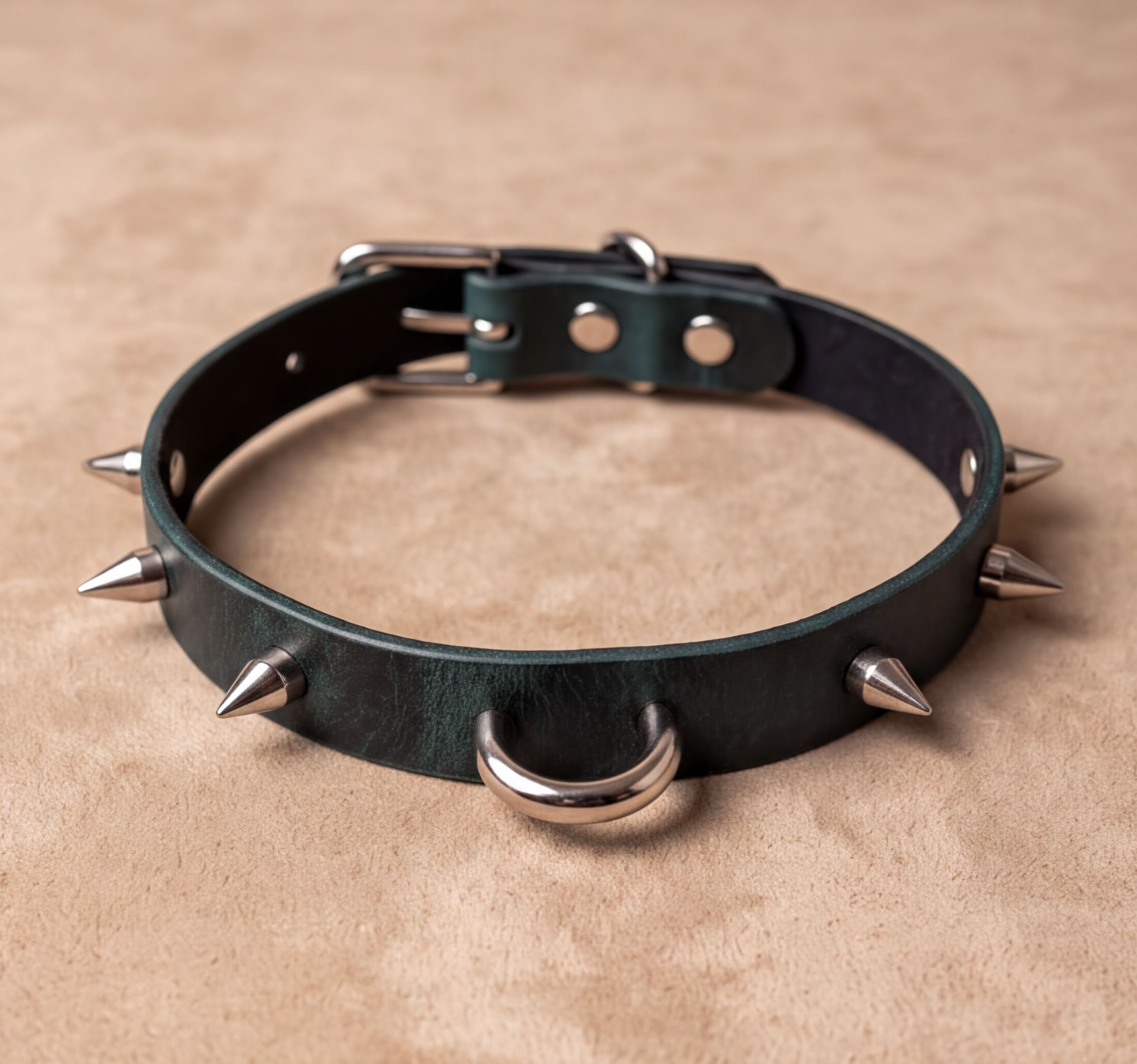 A green leather collar with spikes protruding from it, resting on a beige surface.