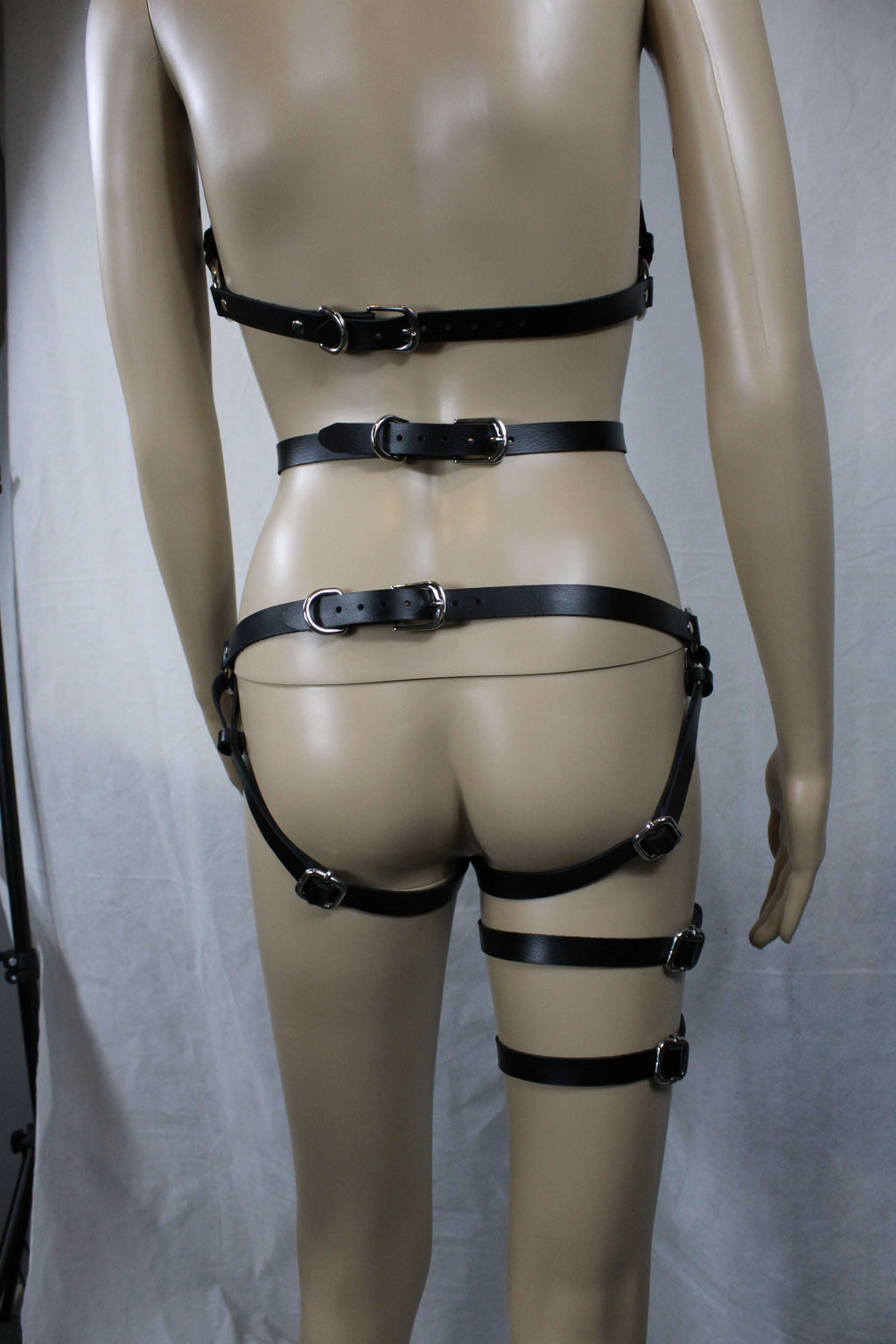 A mannequin wearing a set of leather straps with buckles, which appear to be designed for use in BDSM or BDSM-related activities.