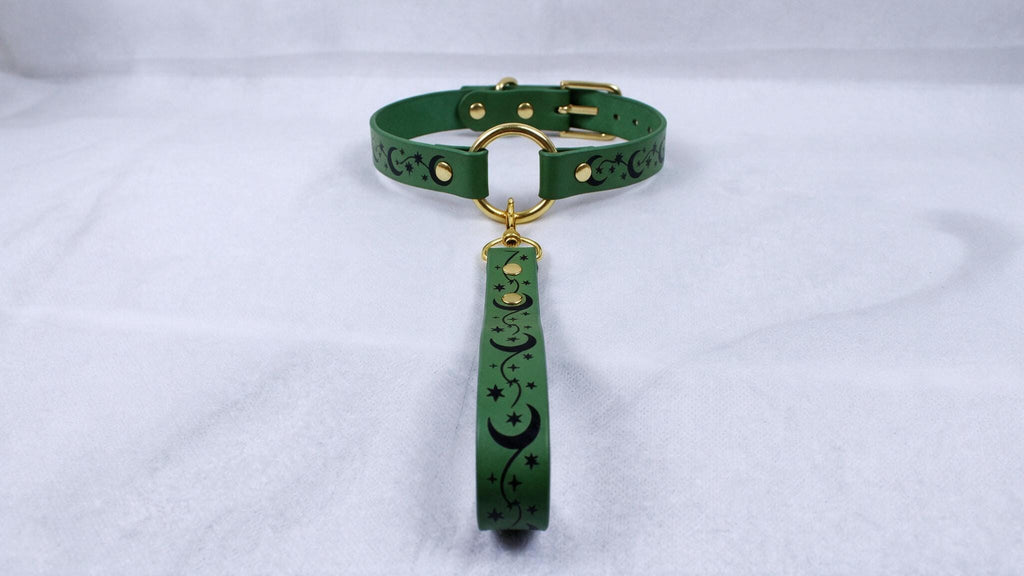 A green collar with a gold buckle and a black star-and-crescent design on the strap.