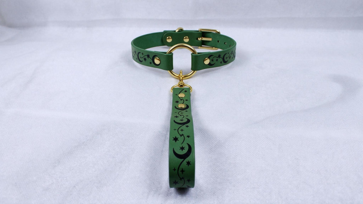A green collar with a gold buckle and a black star-and-crescent design on the strap.