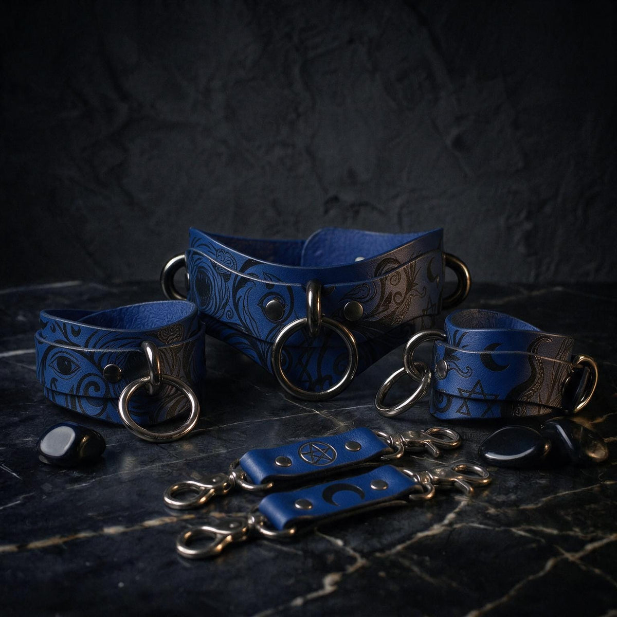 A collection of blue leather straps with metal rings and buckles, arranged on a dark surface.
