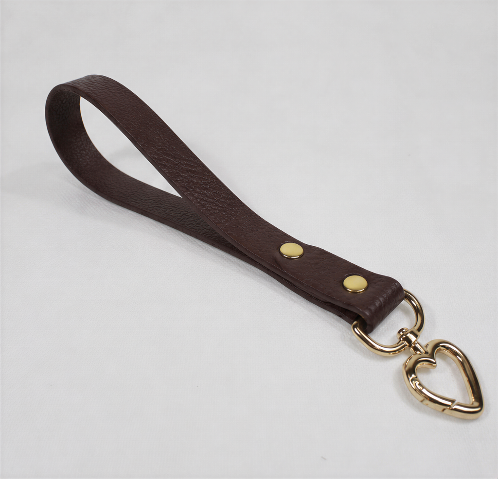 A brown leather strap with a heart-shaped metal clasp attached to it.