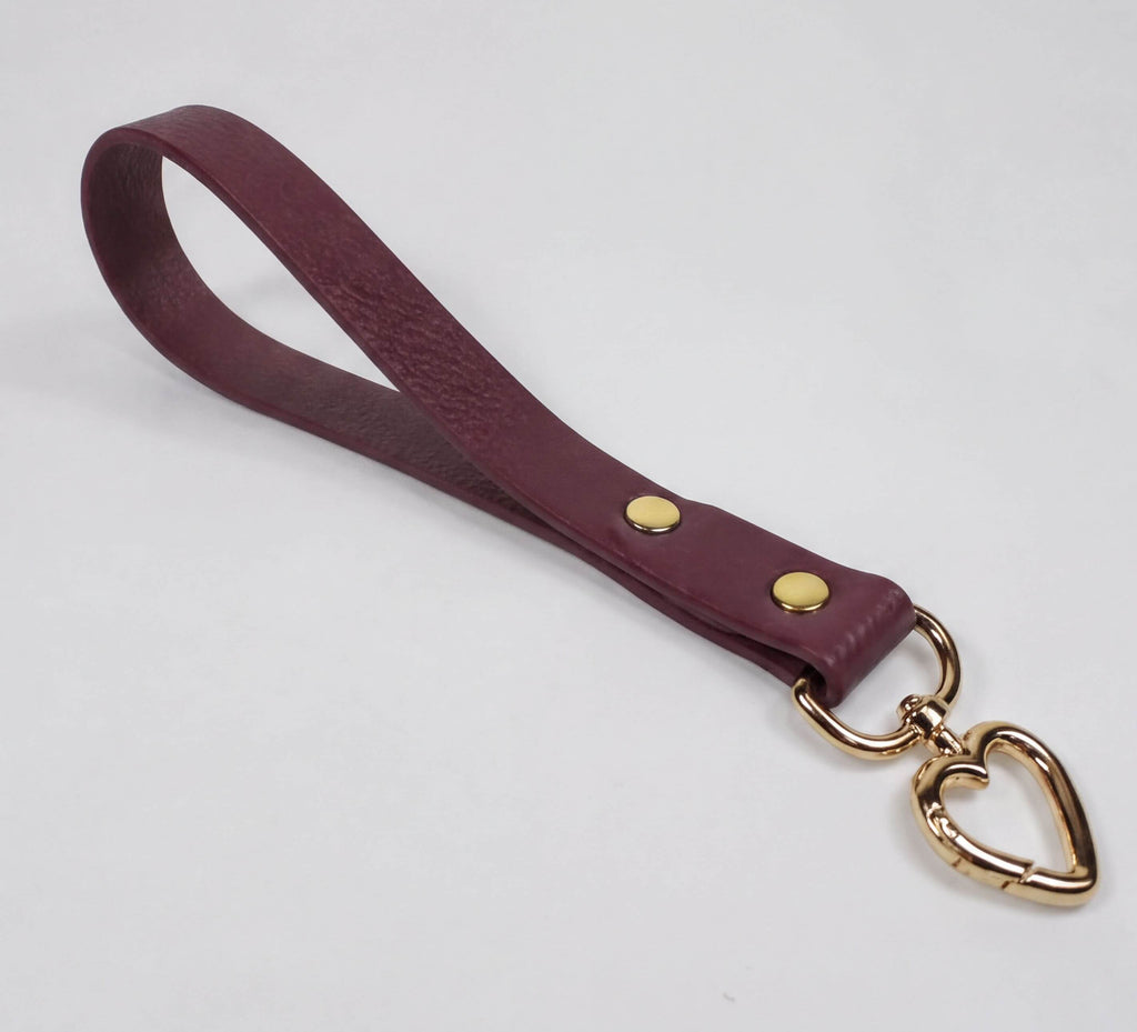 A burgundy leather strap with a heart-shaped metal clasp attached to it.