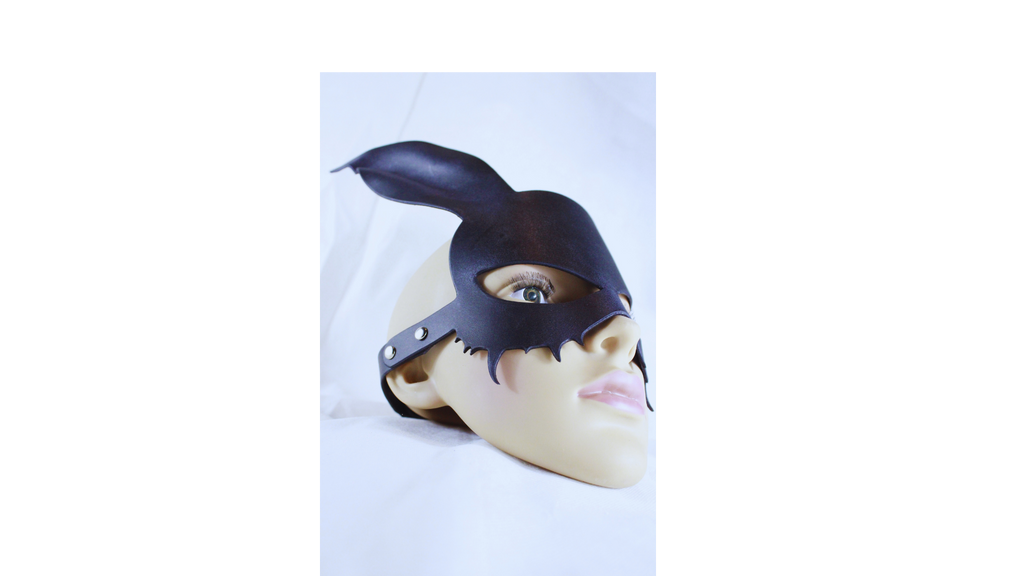 A mannequin head wearing a black mask with a pointed earpiece and a black strap across the forehead.