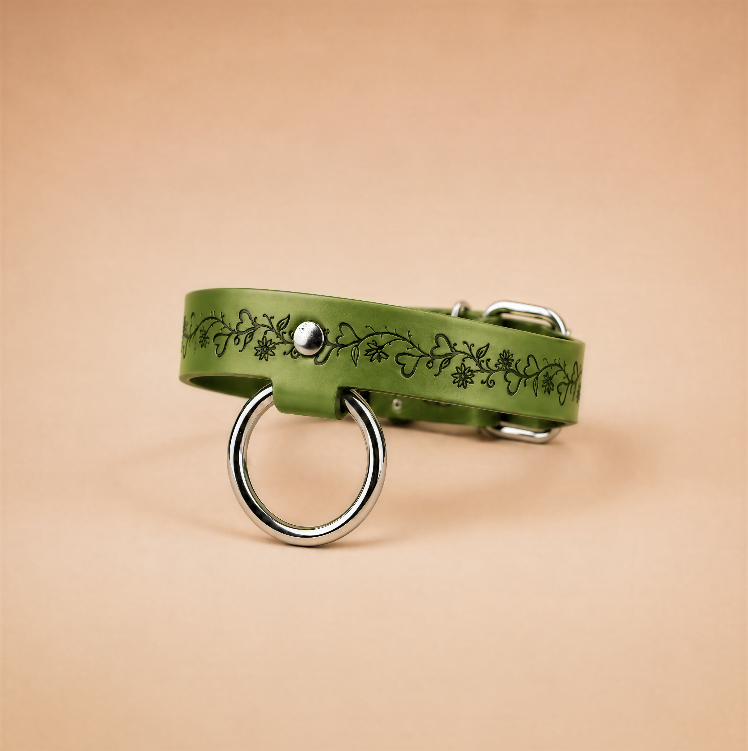 A green dog collar with a metal ring and a floral design on it.