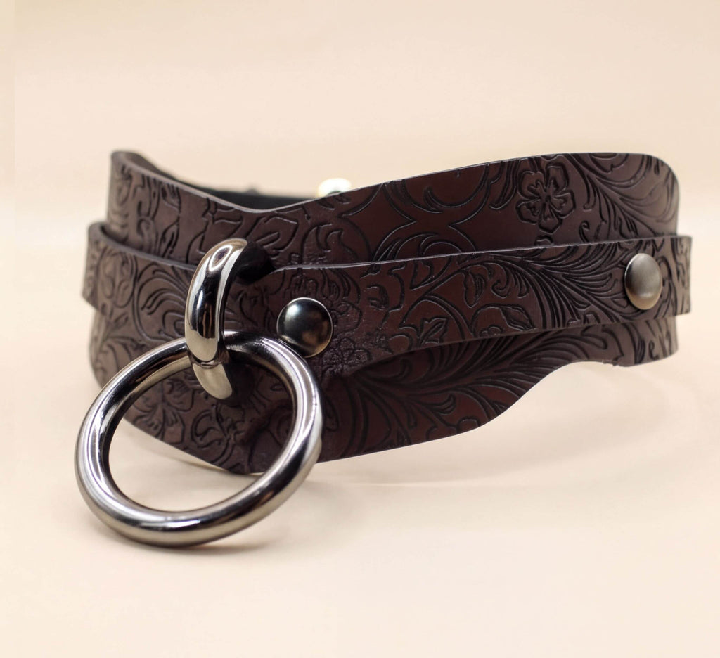 A brown leather choker necklace with a metal ring and two metal buttons.