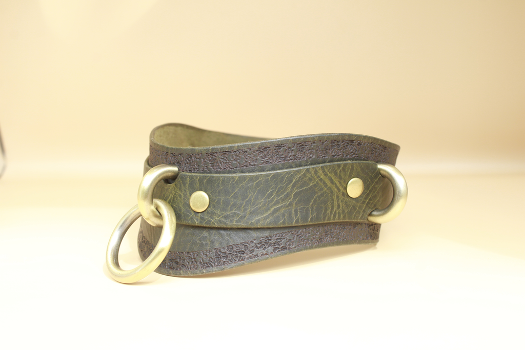 A leather choker necklace with metal rings and a dark green or brown leather band.