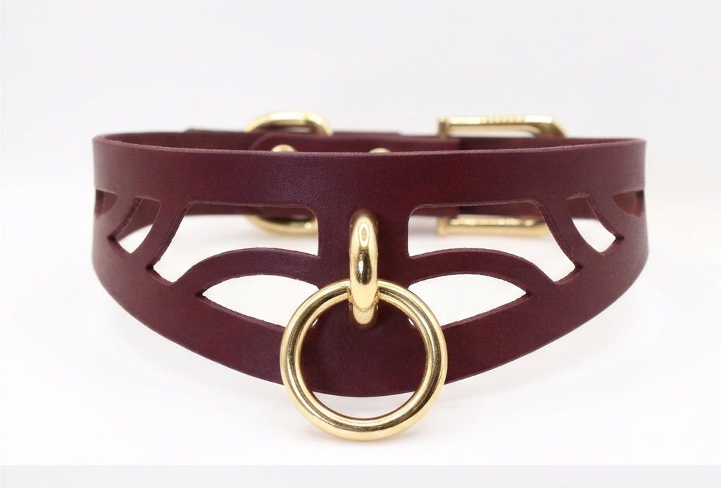 A burgundy leather choker necklace with a gold-colored metal ring and buckle.