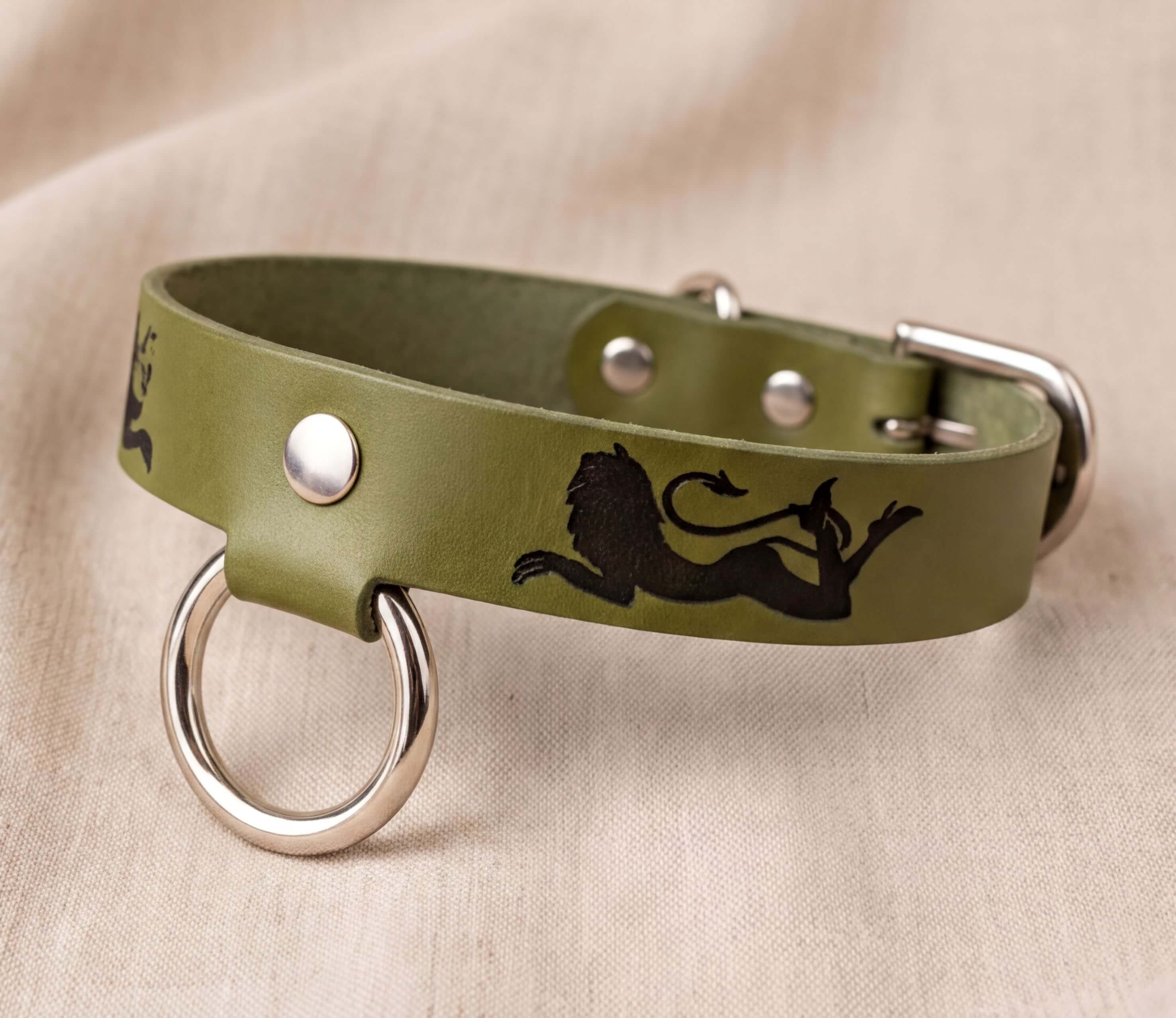 A green leather dog collar with a lion silhouette design and metal rings.