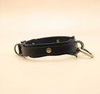 A black leather collar with metal rings and a buckle.
