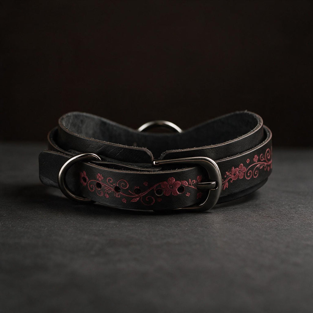A black leather belt with a floral design on it, resting on a dark surface.