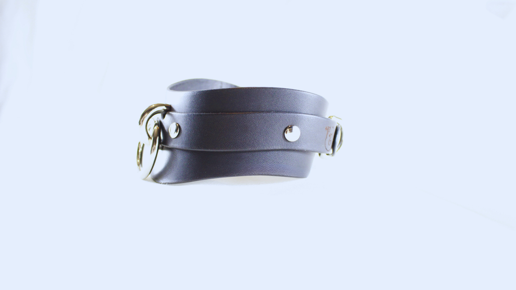A black leather choker necklace with metal studs and a metal clasp.