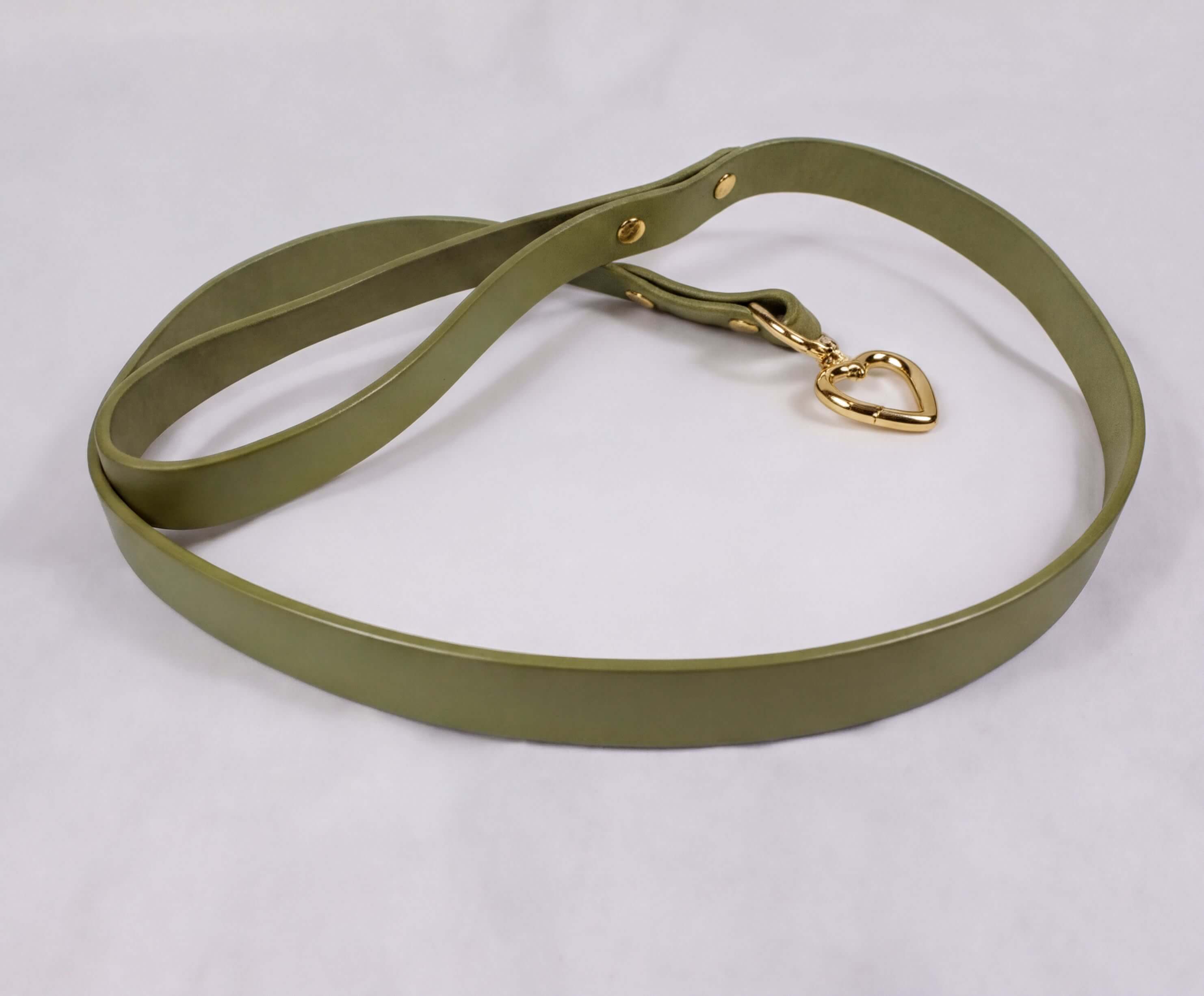 A green leather leash with a gold heart-shaped charm attached.